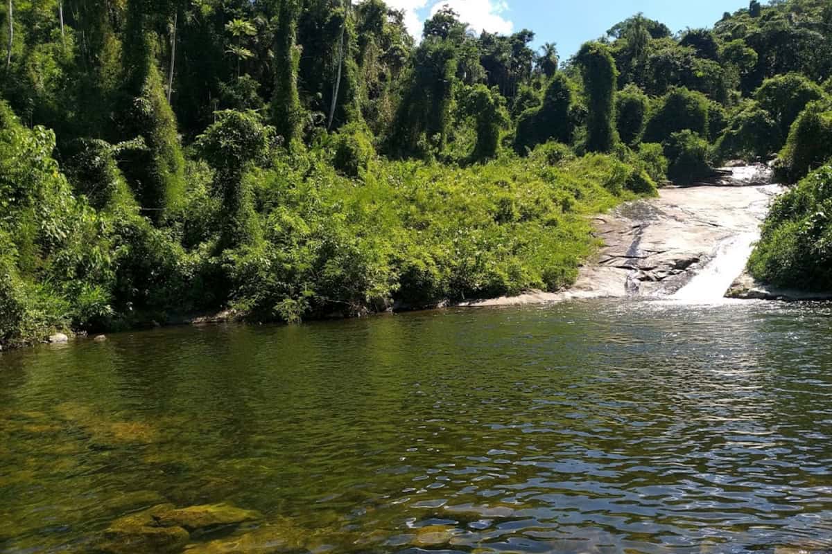 Cachoeira da Graúna com grande poço e laje inclinada, cercada por mata