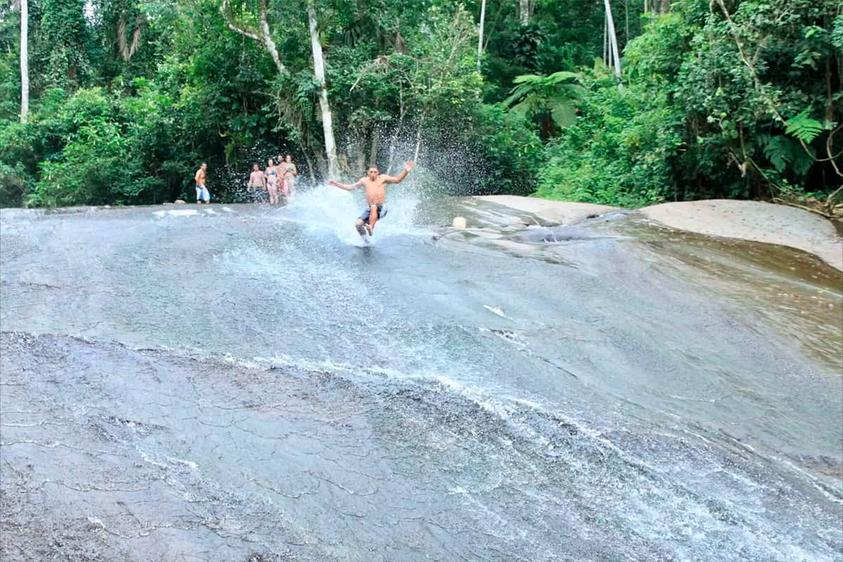 Cachoeira do Tobogã em Paraty, grande laje inclinada com visitantes escorregando até o poço
