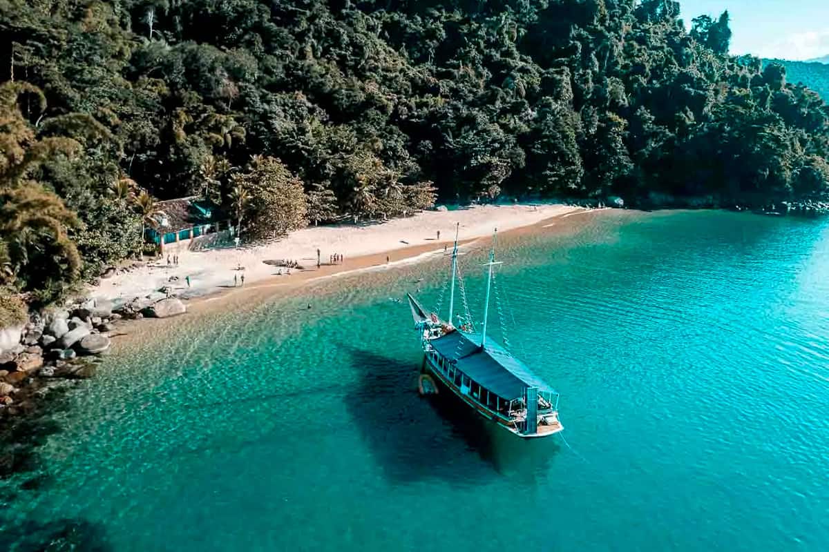 Praia da Lula com mar verde-esmeralda e faixa de areia clara cercada de mata