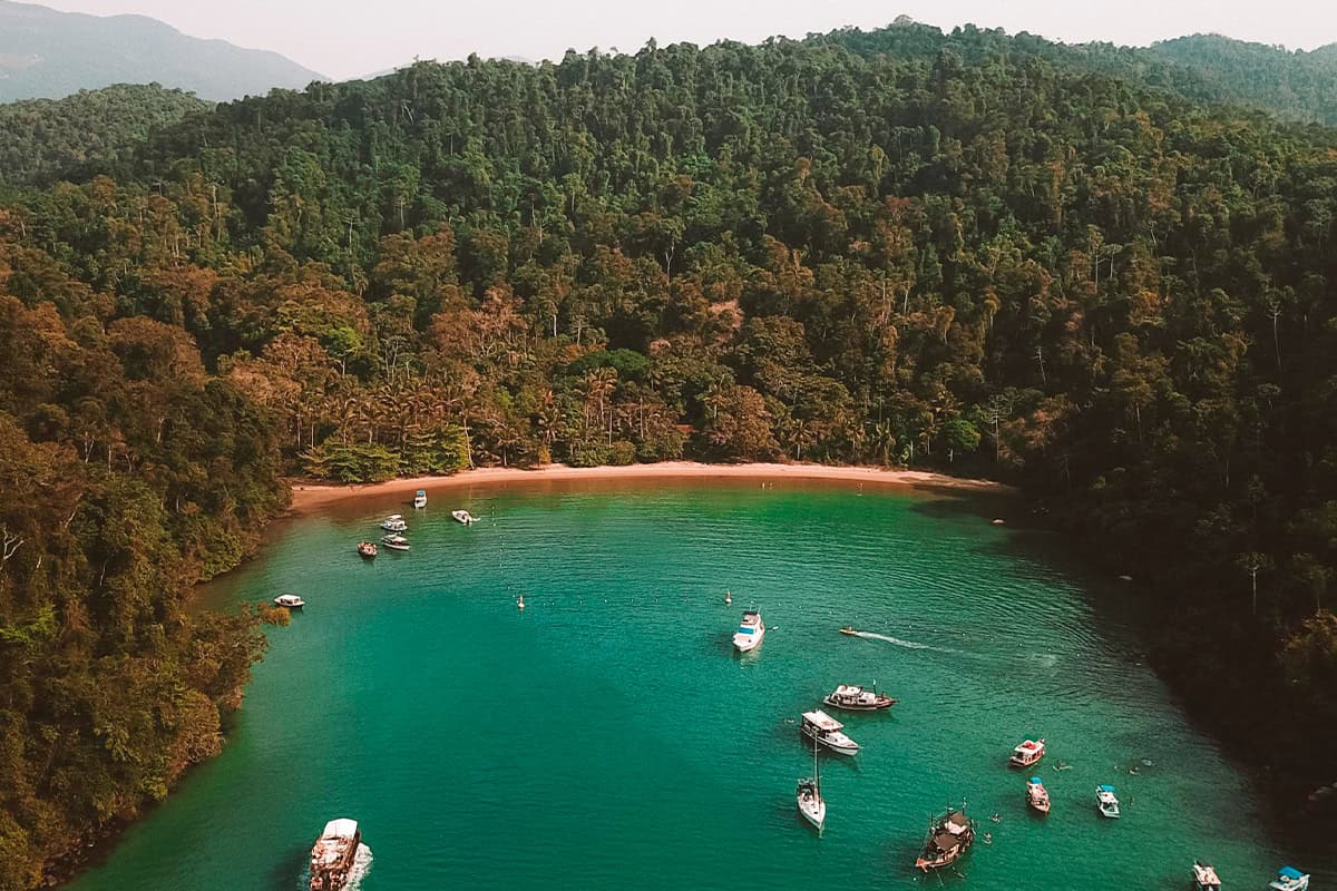 Praia Vermelha com areia fina levemente avermelhada e mar calmo e cristalino